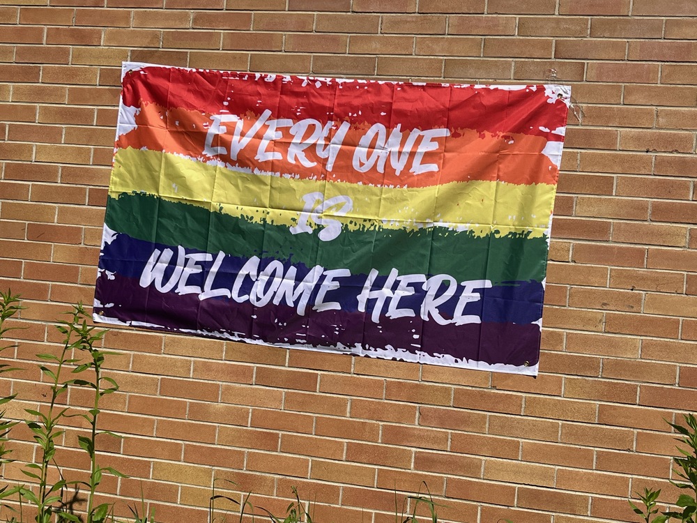 A pride flag that says "Every One is Welcome Here'