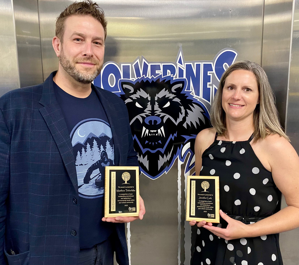 Two teachers in a photo, each holding a plaque.