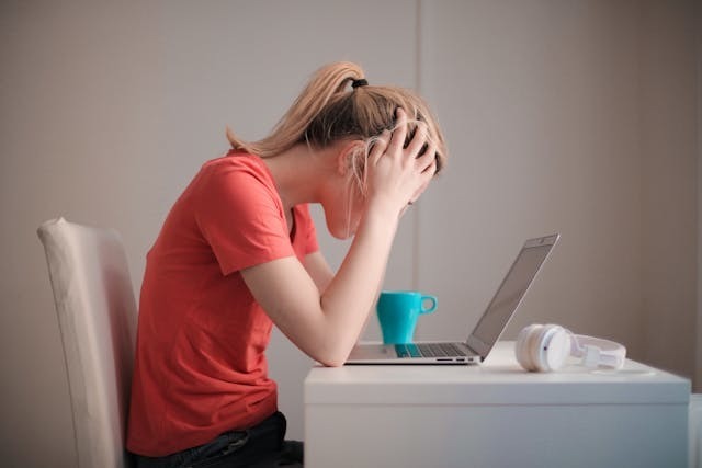 This photo features a young woman at her desk and she is anxious.